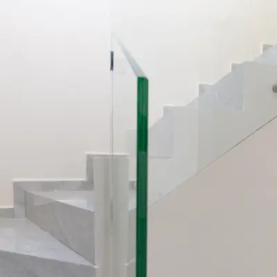 Barandal de cristal templado con herrajes de acero en la escalera