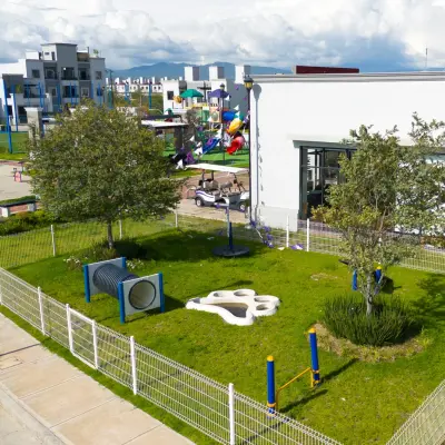 Área verde cercada para mascotas, junto al área de juegos