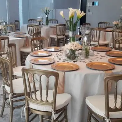 Mesa redonda montada para banquete con vajilla dorada